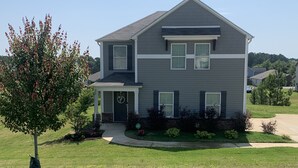 A two-story house with a front porch, a garage, and a well-maintained lawn.