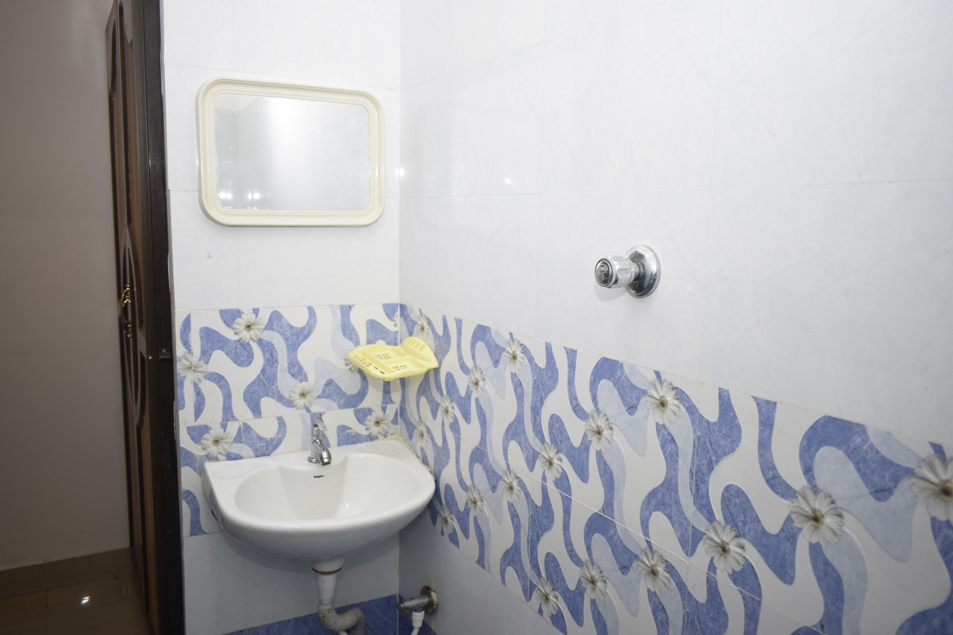 A bathroom with a white sink, a mirror, and patterned tiles.