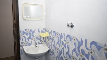 A bathroom with a white sink, a mirror, and patterned tiles.