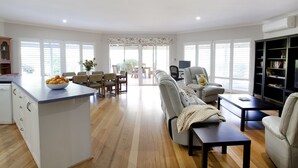 A spacious living area with a kitchen island, a sofa, a coffee table, and a bookshelf. - Twin Gums: Large family home, beautiful gardens on banks of Denmark River (Denmark)