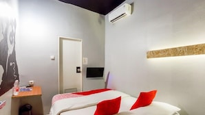 Ein Hotelzimmer mit Bett, Schreibtisch und einem an der Wand befestigten Fernseher.
