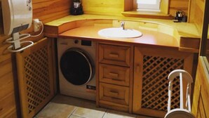 A compact wooden cabin bathroom with a washing machine, a sink, and a window. - Chez_vanilles_des_isles (L'Isle-sur-la-Sorgue)