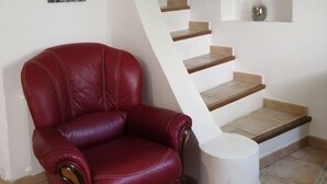A red leather chair, a staircase with beige steps, and a small white table. - Chez_vanilles_des_isles (L'Isle-sur-la-Sorgue)