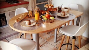 A breakfast table with a variety of food items, including bread, fruits, and a glass of orange juice. - Chez_vanilles_des_isles (L'Isle-sur-la-Sorgue)