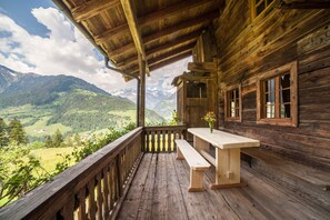 A wooden cabin with a balcony overlooking a mountainous landscape. - Chalet "Schnitzers Ferienheisl" with Mountain View, Garden & Wi-Fi (Sankt Leonhard in Passeier)