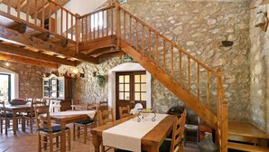 Un comedor con mobiliario de madera, una pared de piedra y una escalera de madera.