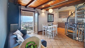 A cozy living area with a sofa, dining table, and kitchen area with a staircase. - Vacation Apartment in Beautiful Vineyard 'Crotto Palma' with Lake View & Wi-Fi (Dongo)