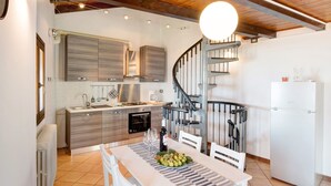 A modern kitchen with a central island, a built-in oven, and a spiral staircase. - Vacation Apartment in Beautiful Vineyard 'Crotto Palma' with Lake View & Wi-Fi (Dongo)