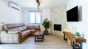 Un salon avec un canapé, une table basse, une cheminée, un téléviseur et un mur en pierre.