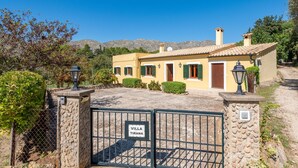 A villa with a stone gate, a sign reading 'Villa Tirana,' and a mountainous backdrop.