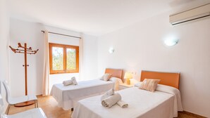 A hotel room with two beds, a chair, a coat rack, and a window.
