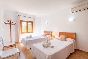 A hotel room with two beds, a chair, a coat rack, and a window.