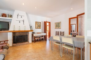 A dining area with a fireplace, a television, and a dining table with chairs.