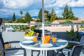 A round table with a white tablecloth, a bowl of fruit, and glasses of orange juice.