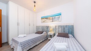 A bedroom with two beds, a wooden wardrobe, a painting, and a lamp. - Vacation Home "Casa Cantino" with Pool, Wi-Fi & Terrace (Santa Margalida)