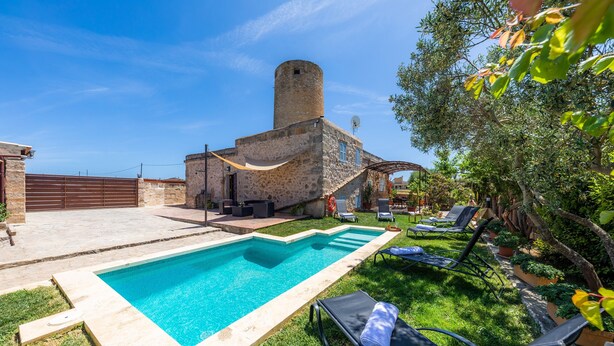 A swimming pool, lounge chairs, and a stone building with a tower. - Pet-Friendly Vacation Home Moli Den Barret with Mountain View, Pool & Wi-Fi (Santa Margalida)