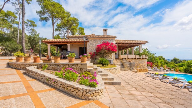 Una villa con piscina, mobiliario exterior y un camino de piedra.