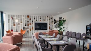 Une salle de conférence moderne équipée d’une longue table, de plusieurs chaises, d’un téléviseur et d’une bibliothèque.