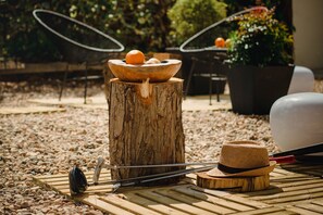 A rustic outdoor setting with a wooden bowl on a tree stump, a hat, and a pair of scissors on a wooden surface. - A House In Estoril (Cascais)
