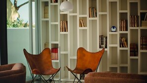 Une pièce avec une bibliothèque remplie de livres, deux fauteuils en cuir et un lampadaire.
