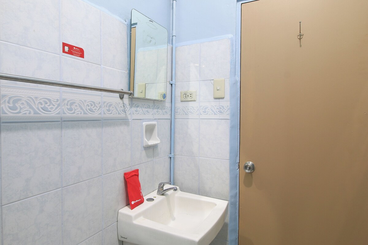 A bathroom with a hand dryer, a sink, a towel dispenser, and a door.