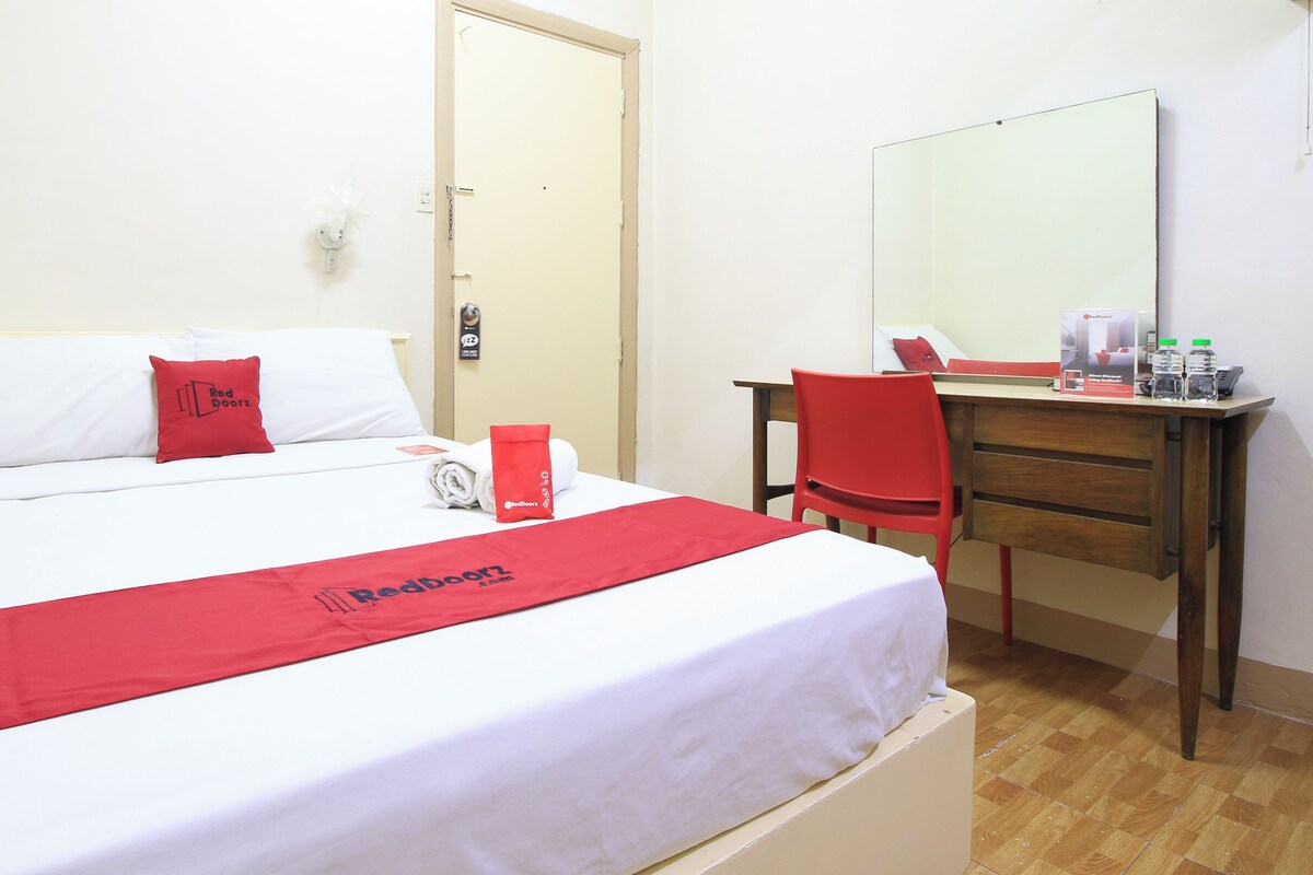 A hotel room with a bed, a desk, and a chair.