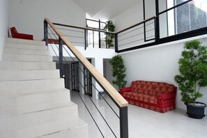 Una escalera con barandilla de madera y pasamanos de metal negro, que conduce a un nivel superior.