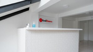A reception desk with a white textured surface and a logo for RedDoorz. - Reddoorz @ Demangan Sari Residence (Depok)