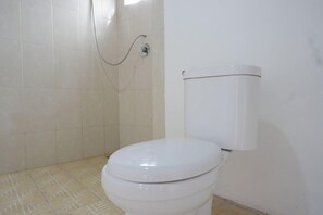 Un baño con inodoro blanco, ducha y paredes de azulejos.