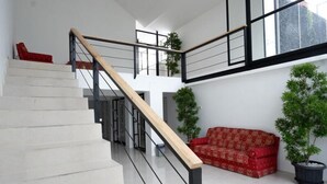 A staircase with a wooden handrail and black metal railings, leading to an upper level. - Reddoorz @ Demangan Sari Residence (Depok)