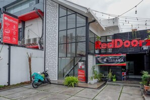 Un edificio con un letrero RedDoorZ, un restaurante Legawa y una scooter estacionada.