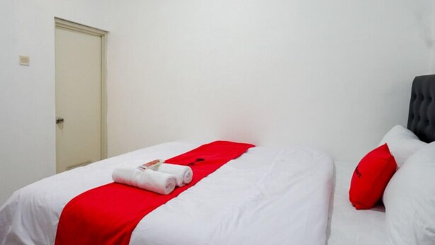 Una habitación de hotel con una cama, un edredón rojo y una almohada blanca.