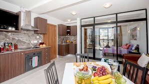 A modern kitchen with a dining area, a large window, and a view of the city. - GetawaysMalta - Harbour Lights Seafront Penthouse with Terrace St Paul's Bay (St Paul's Bay)