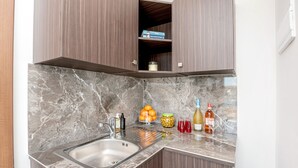A kitchen with a marble countertop, a stainless steel sink, and wooden cabinets. - GetawaysMalta - Harbour Lights Seafront Penthouse with Terrace St Paul's Bay (St Paul's Bay)