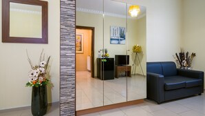 Un salon moderne avec un grand miroir, un canapé bleu, un vase décoratif et un téléviseur.