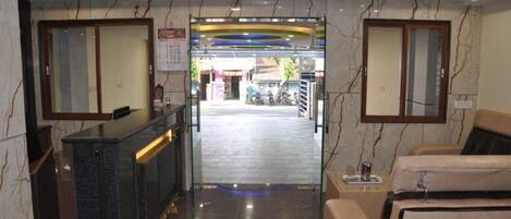 Hall dell'hotel con reception, area salotto e vista sulla strada.
