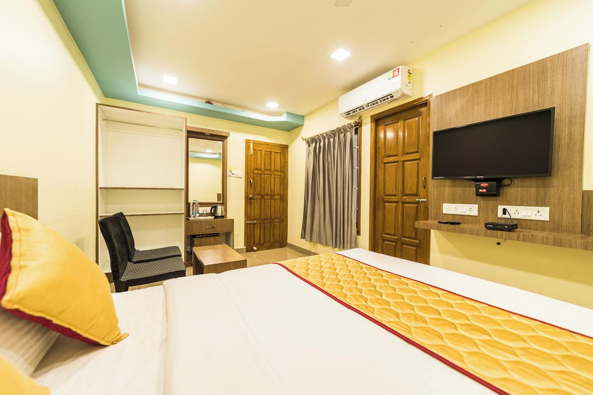 Una habitación de hotel con una cama, un escritorio, una silla, un televisor y un aire acondicionado.