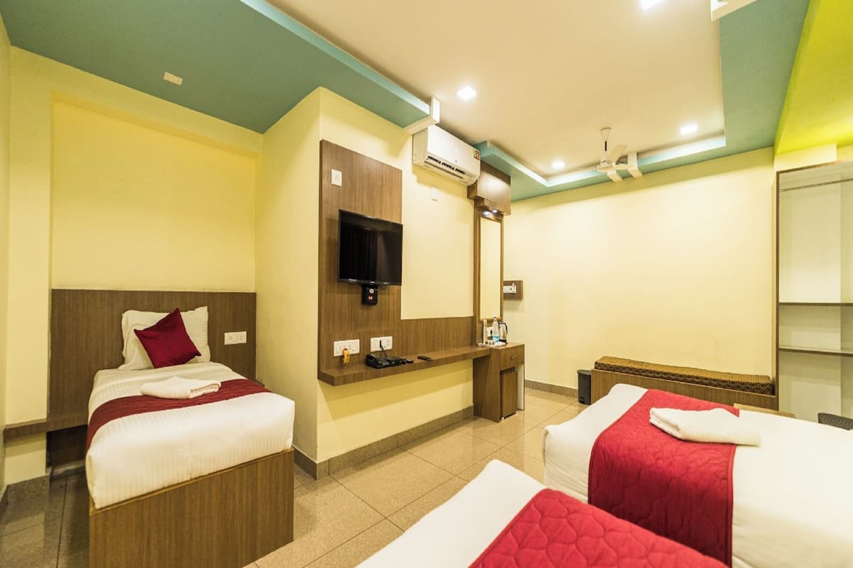 Habitación de hotel con dos camas, televisor, escritorio y espejo.