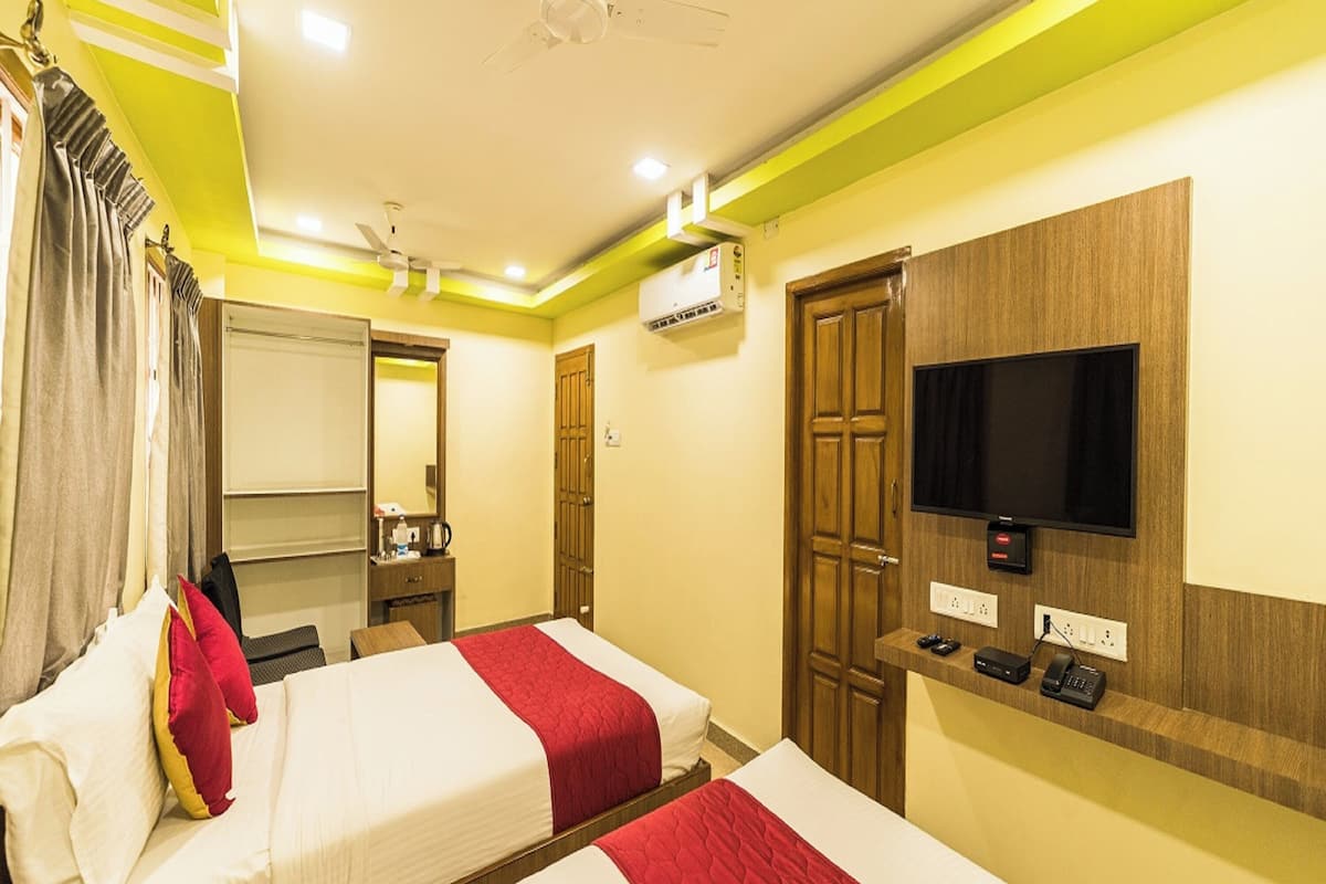 Habitación de hotel con dos camas, televisor, espejo, armario y aire acondicionado.
