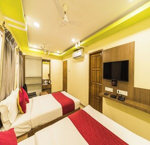 Habitación de hotel con dos camas, televisor, espejo, armario y aire acondicionado.