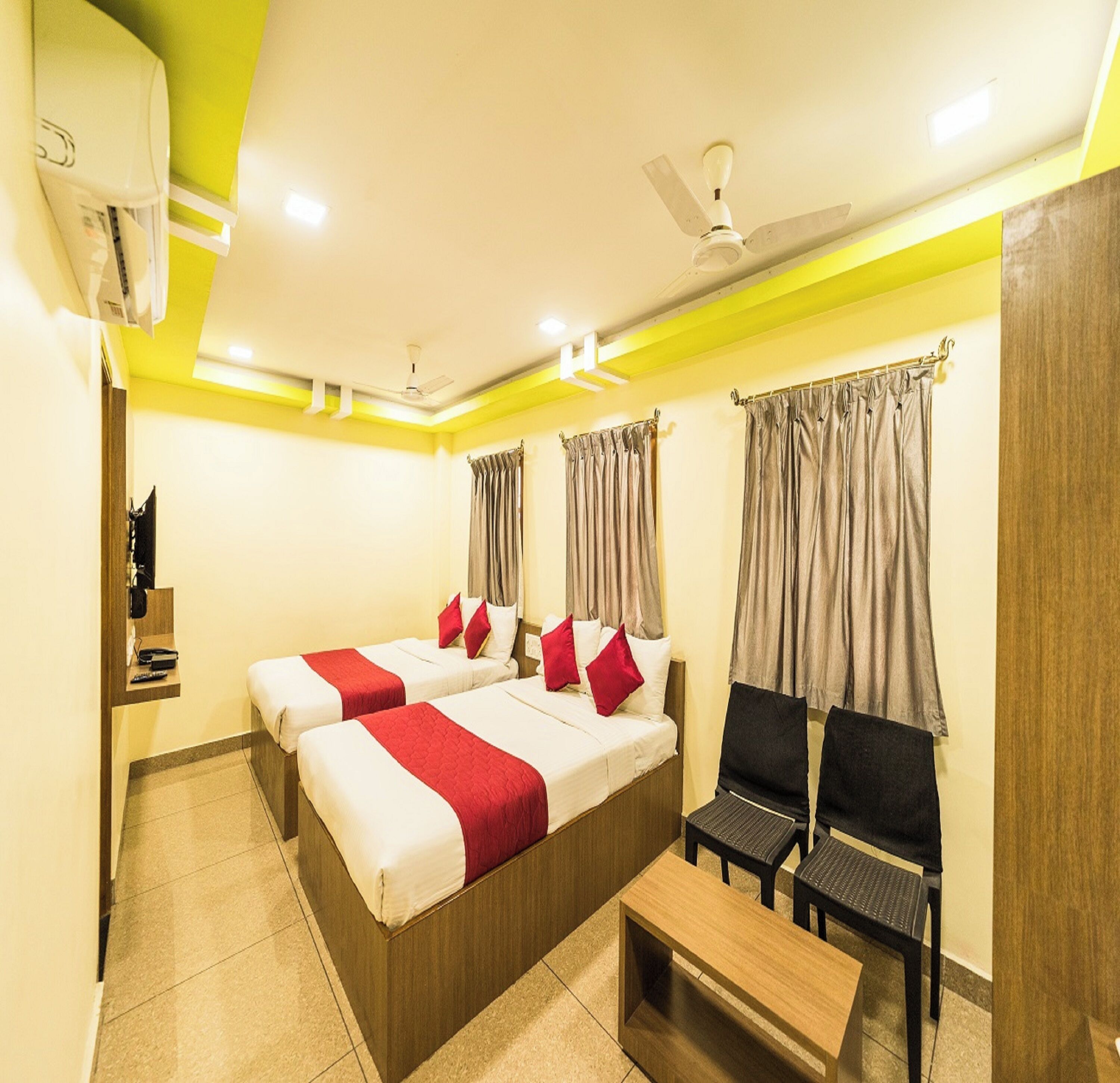 A hotel room with two beds, a desk, and a chair. There is a ceiling fan and an air conditioning unit.