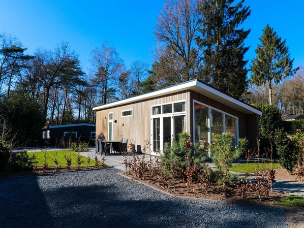Een modern gebouw met een houten gevel, grote ramen en een grindpad.
