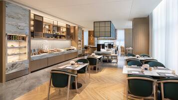 Un restaurante moderno con barra de mármol, armarios de madera y sillas tapizadas en verde.