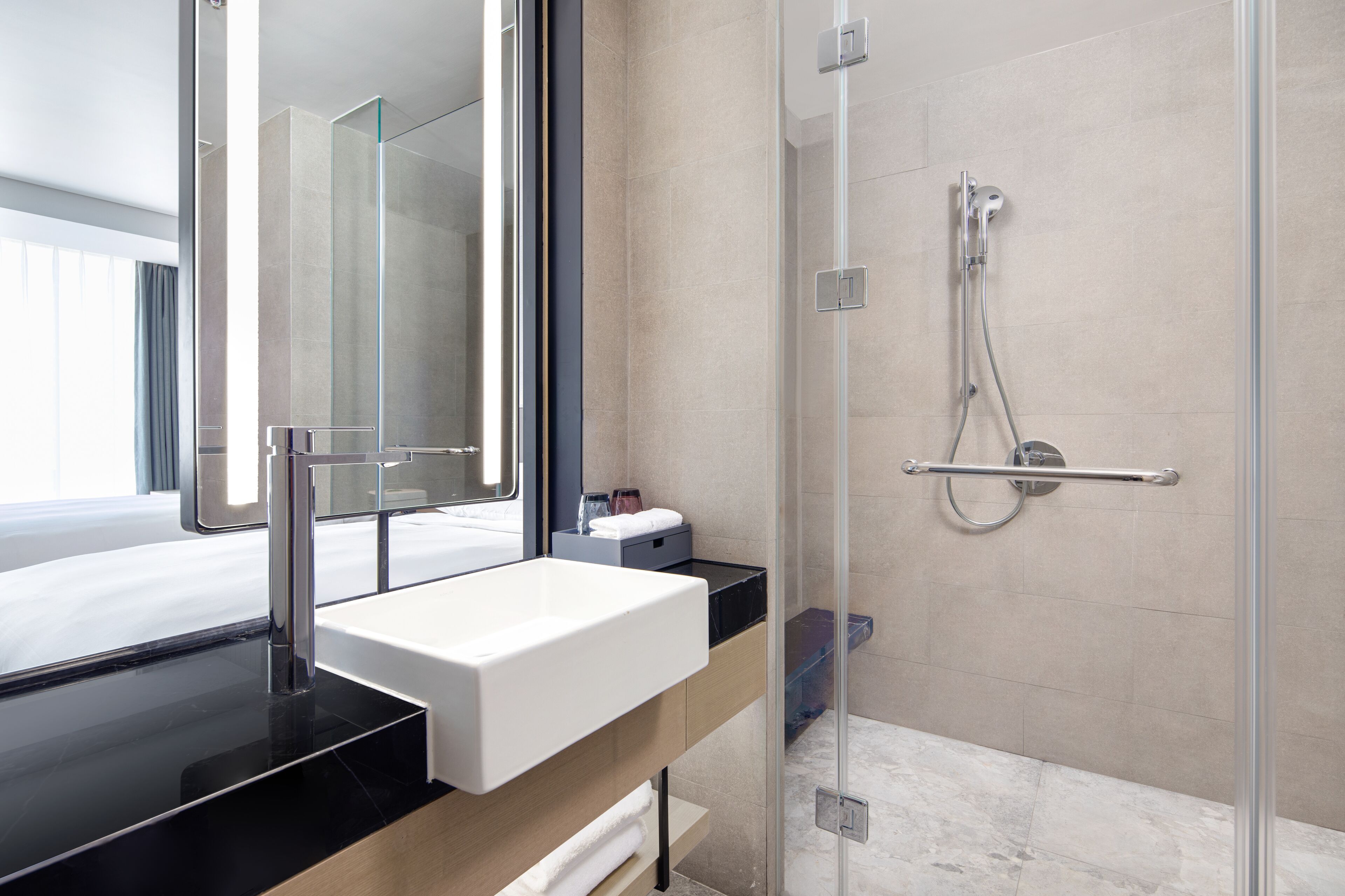 Un baño moderno con cabina de ducha de vidrio, un lavabo blanco y un espejo grande.