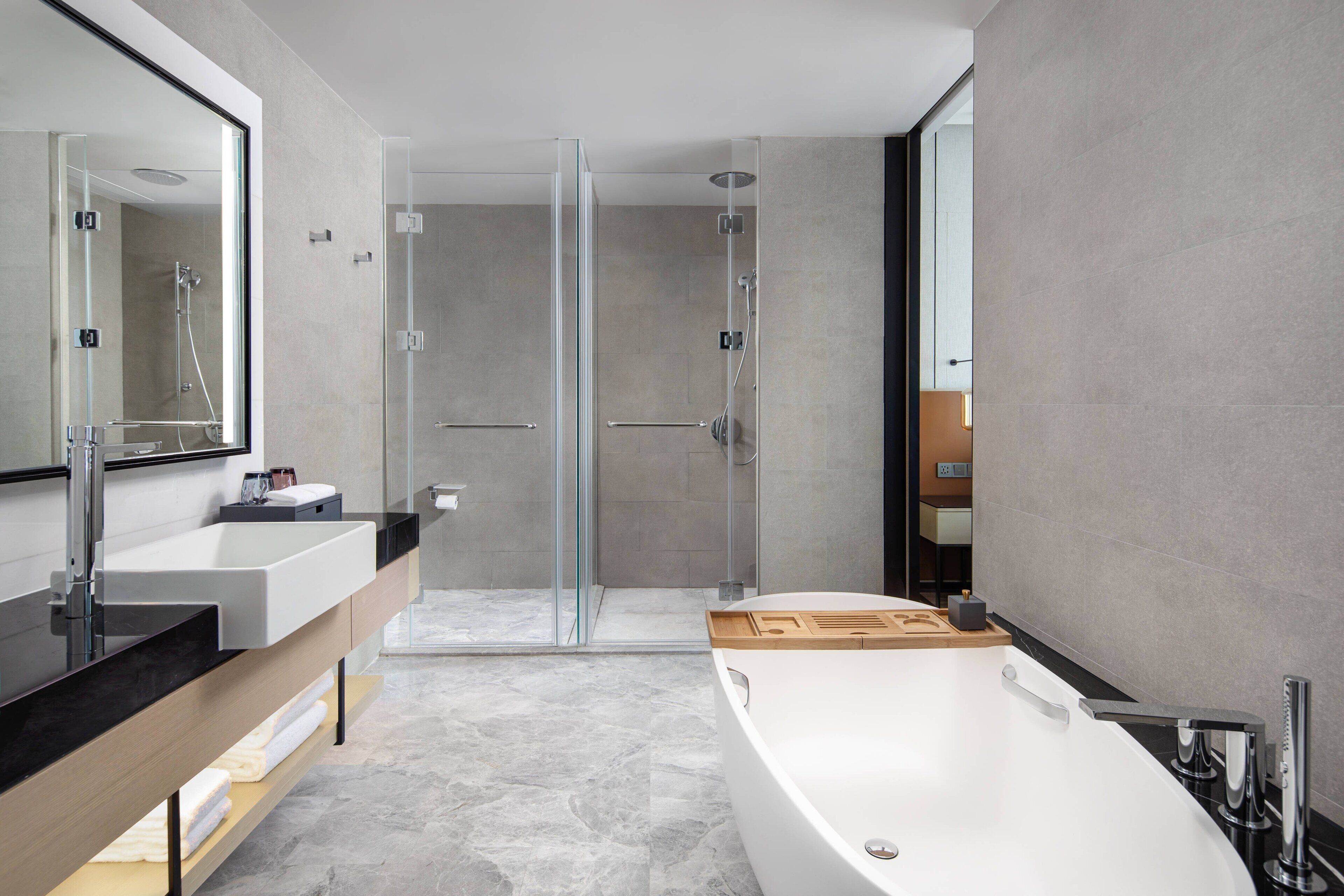 A modern bathroom with a large bathtub, a glass-enclosed shower, and a vanity with a mirror.