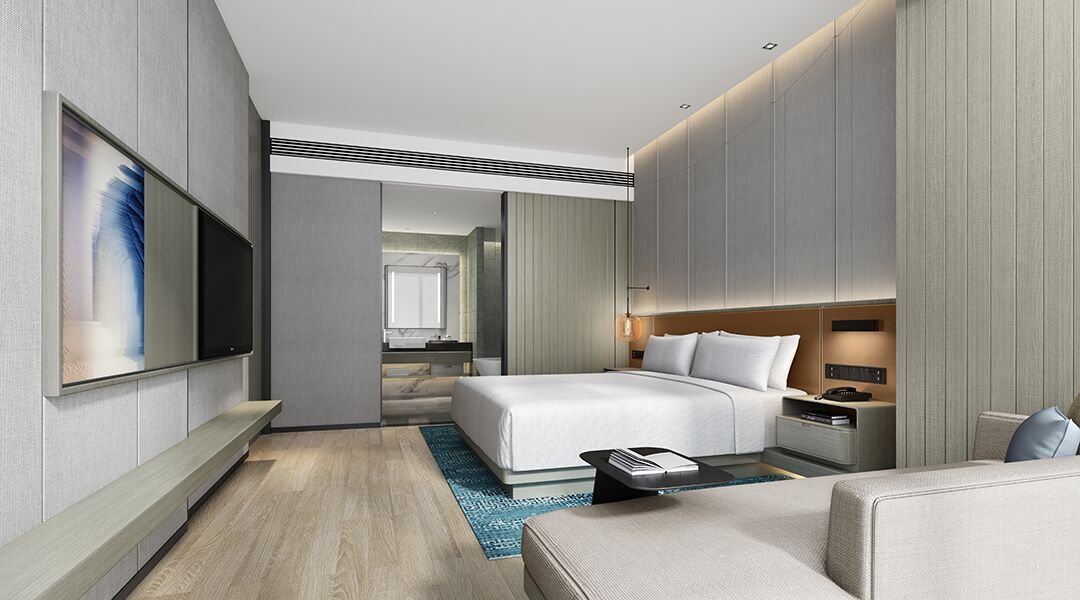 Una habitación de hotel moderna con una cama grande, mesitas de noche, un televisor de pantalla plana y una zona de estar.
