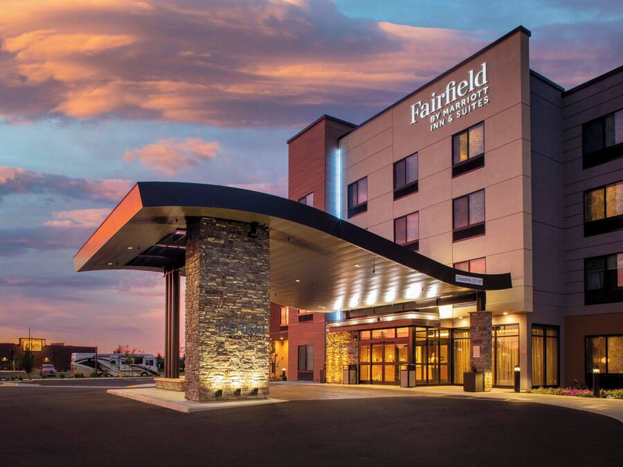 A Fairfield Inn & Suites hotel with a modern design, featuring a prominent entrance and a stone pillar.