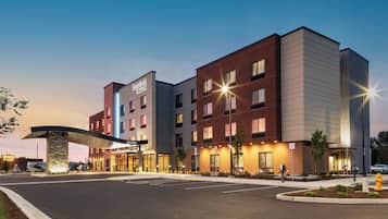 A modern hotel with a curved entrance, multiple floors, and a well-lit facade.