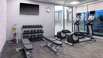 A gym with a bench, dumbbells, and cardio equipment.