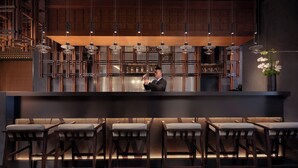 A bar area with a bartender, wooden paneling, hanging pendant lights, and bar stools. - Yancheng Marriott Hotel (Yancheng)